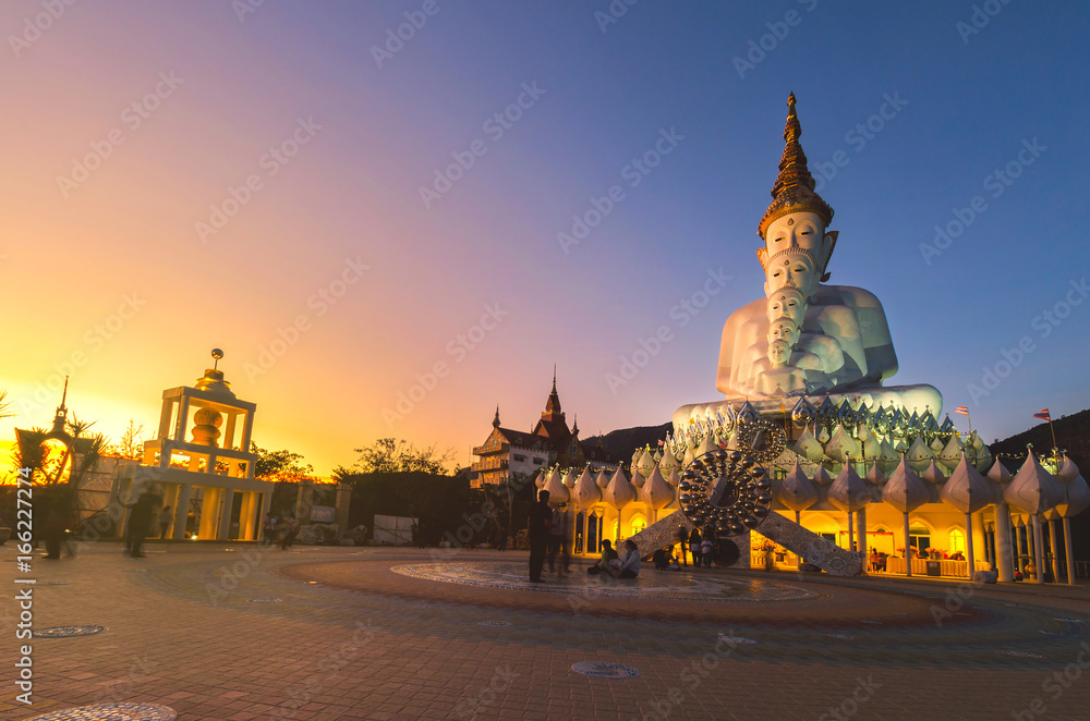 Beautiful of white Buddha immage in Thailand, The temple unseen on the mountain at sunset with golden hour and blue sky.
