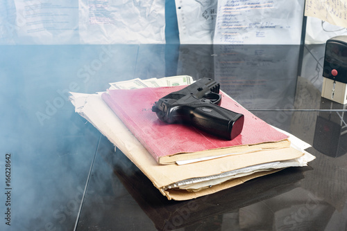 Folder with documents with a gun on the table