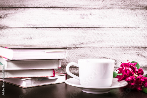 Stack of books, cup of coffee and Rhododendron flowers on wooden background. cover, card. copy space.