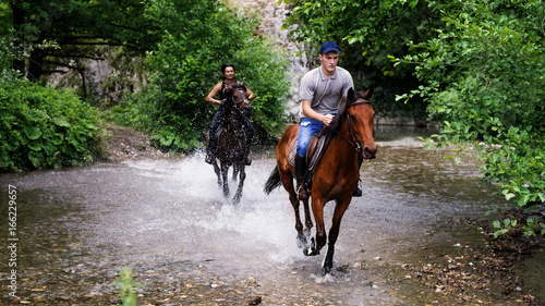 Group of friends riding horses on the river © romul014