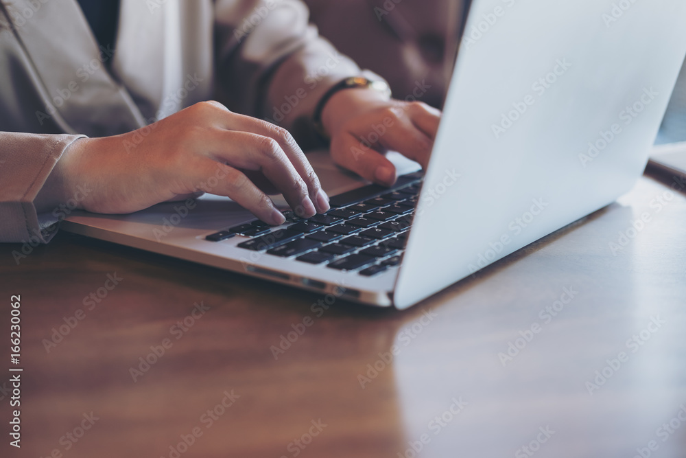 Closeup image of an Asian business woman working and typing on laptop keyboard in office Closeup image of an Asian business woman working and typing on laptop keyboard in office