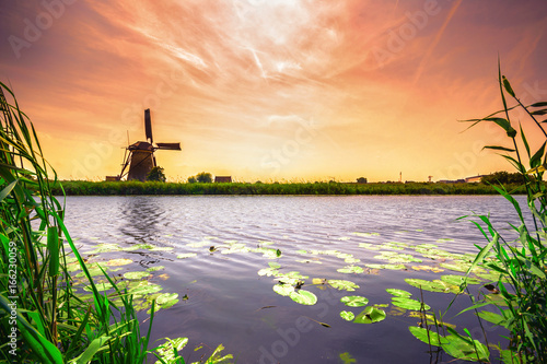 Photography Traditional village with dutch windmills and river at sunset, Holland, Netherlands