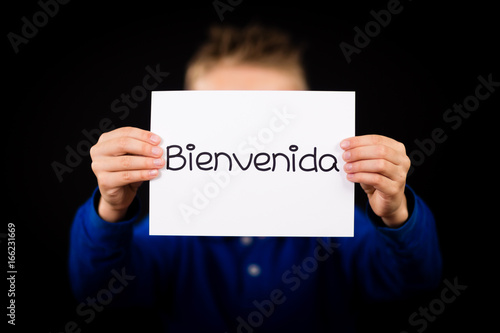 Child holding sign with Spanish word Bienvenida - Welcome