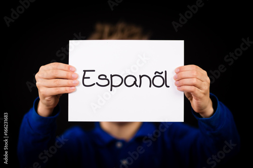 Child holding sign with Spanish word Espanol - Spanish in English
