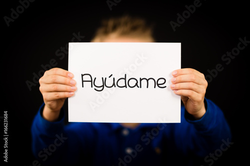 Child holding sign with Spanish word Ayudame - Help Me photo
