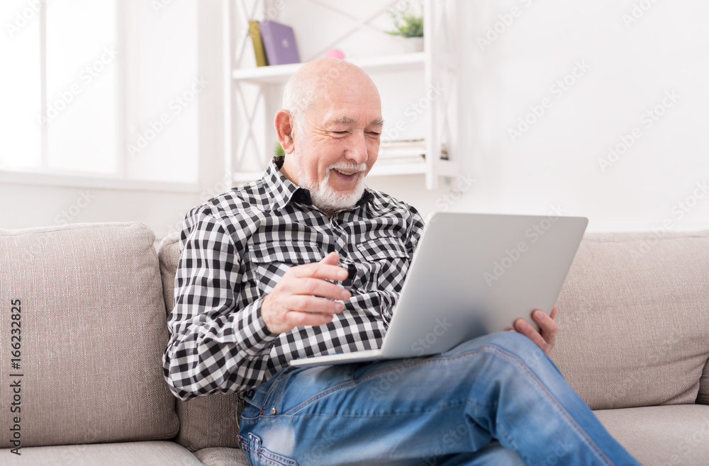 Smiling senior man reading news on laptop Smiling senior man reading news on laptop