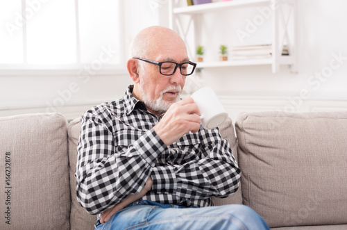 Senior man having cup of coffee in living room
