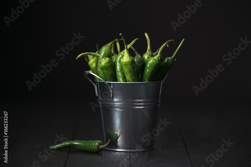 Still life with green chilli pepper on wooden table in moon mystic light