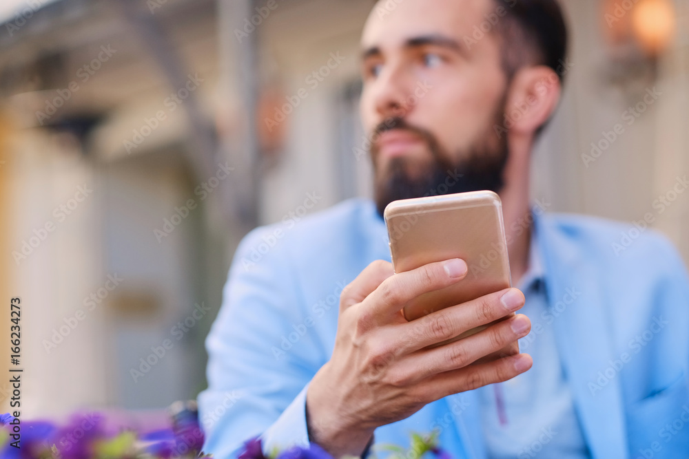 Stylish bearded male in a blue jacket using smartphone. Stylish bearded male in a blue jacket using smartphone.