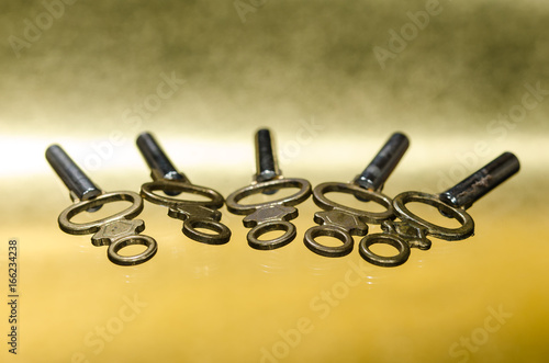 Five Antique Brass Pocket Watch Keys Laying on Golden Surface photo