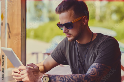 Foto Attractive guy using a tablet PC in a cafe near the window.
