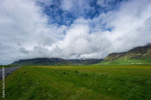 Iceland - Cloud covered green volcanic mountains behind meadow
