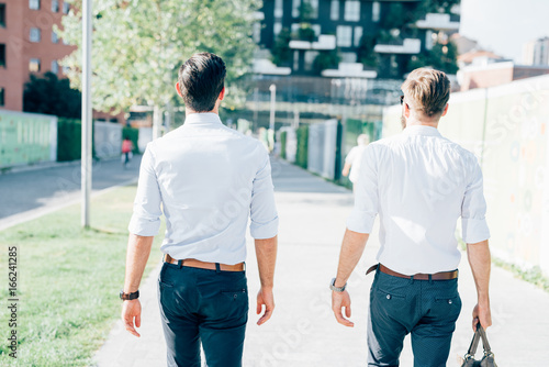 back view of two bearded business men young outdoor walking chatting - business, relaxing concept