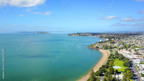 Fototapeta Naklejka Na Ścianę i Meble -  Aerial view on sunny beach with residential suburb on the background. Auckland, New Zealand.
