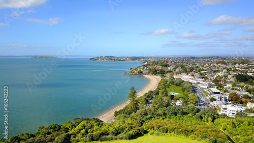 Aerial view on sunny beach with residential suburb on the background. Auckland, New Zealand.