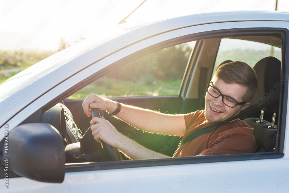 Naklejka premium Happy handsome young man in a brown T-shirt driving a car