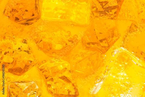 Close-up of ice cubes in drink or orange juice