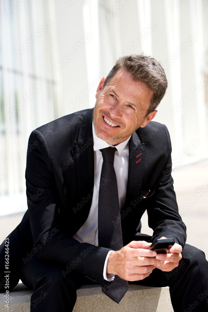 Portrait of businessman sitting and smiling holding mobile phone Portrait of businessman sitting and smiling holding mobile phone