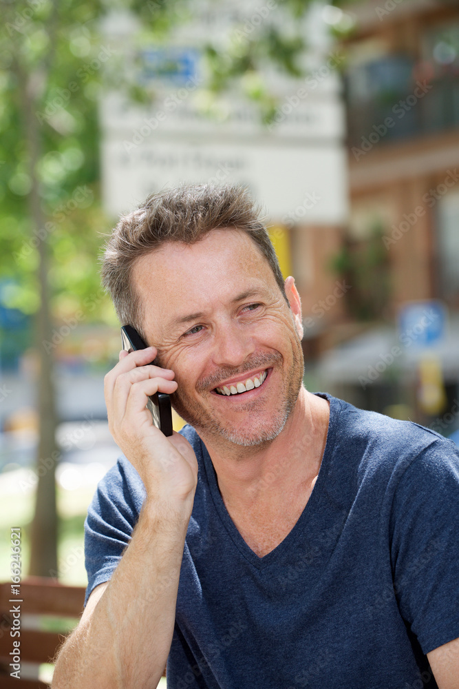 Side of laughing man sitting on park bench with cellphone Side of laughing man sitting on park bench with cellphone