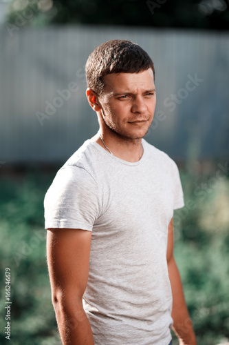 Outdoor portrait of a handsome young man in jeans and gray t-shirt.