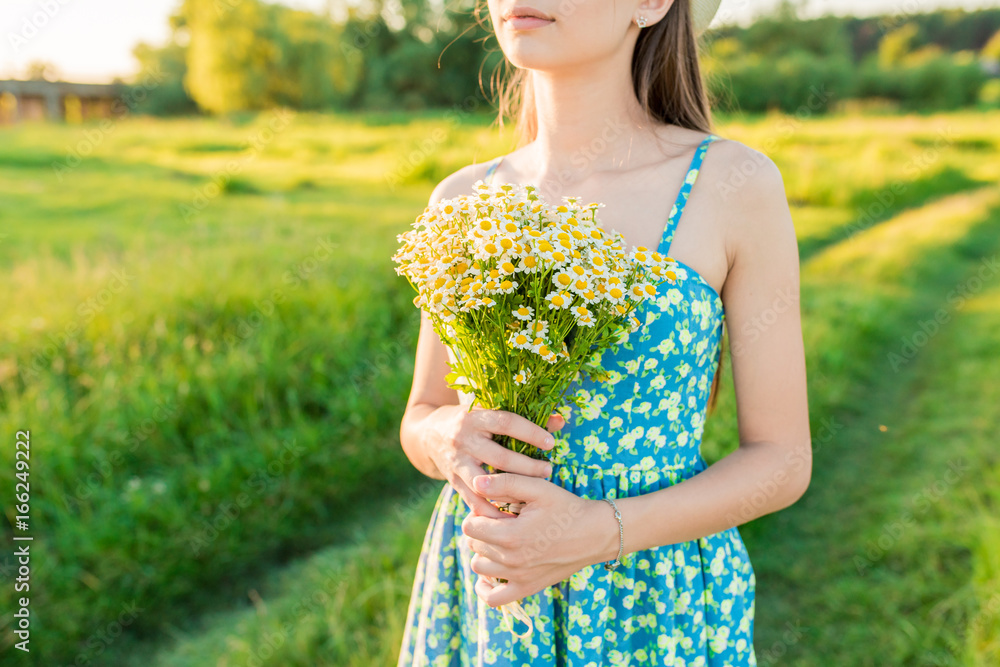 A young girl in a blue dress is holding a bouquet of wildflowers in her hands A young girl in a blue dress is holding a bouquet of wildflowers in her hands