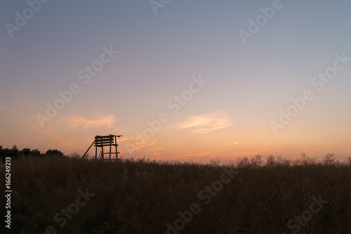 Wooden watchtower located in a field during sunset