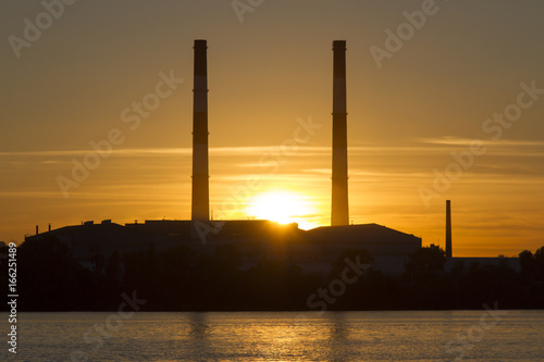 Pipe factory against the background of the river sunset