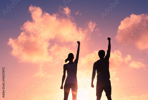 People, power, and victory. Silhouette of confident man and woman with fist in the air.