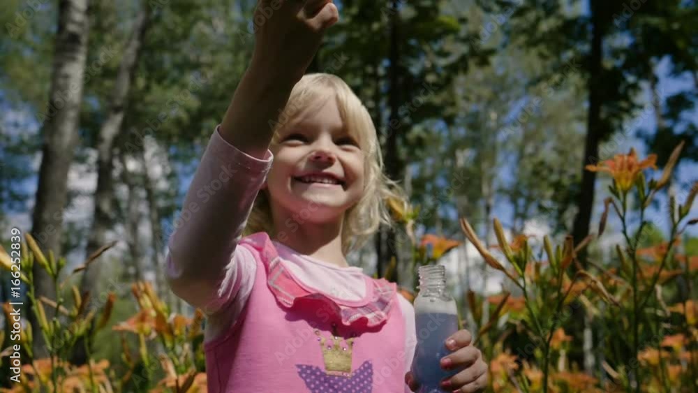The happy blonde little girl playing with soap bubbles in the summer park. Slow motion. HD The happy blonde little girl playing with soap bubbles in the summer park. Slow motion. HD