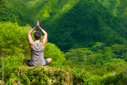 Mind body a spirt. Man meditating in a beautiful lush green mountain setting. 