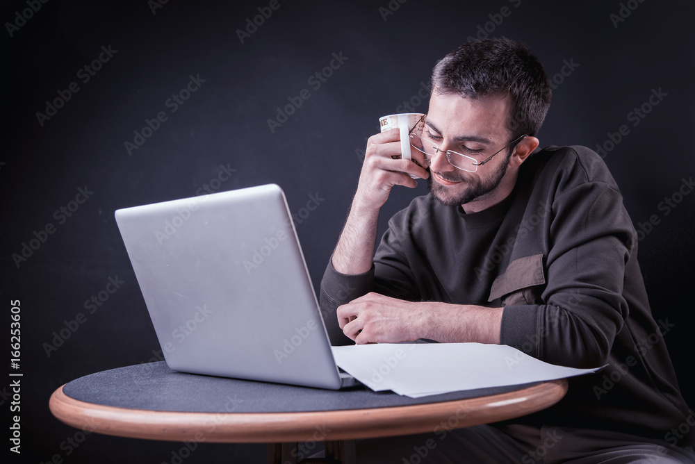 Young man enjoying his coffee and working on laptop, freelance writer or a blogger Young man enjoying his coffee and working on laptop, freelance writer or a blogger