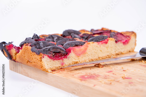 Plum pie on a wooden chopping board on a white background