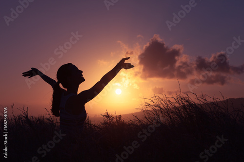 Young woman feeling happy and free in a beautiful, sunset nature setting. 