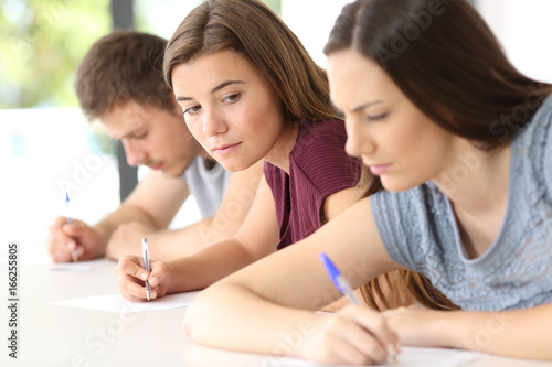 Obraz na plátně Student trying to copy an exam of a classmate