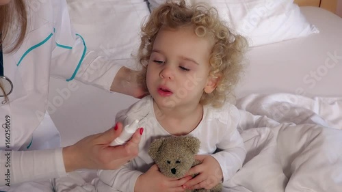 Pediatrician doctor using nasal spray for stuffy nose cute girl patient