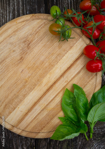 round cutting board and tomatoes on wooden surface