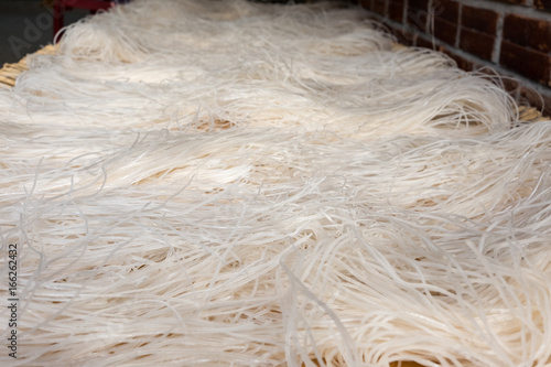 Cooking rice noodles from a flat cake on a wicker bedding. Vietnam, Mekong Delta photo