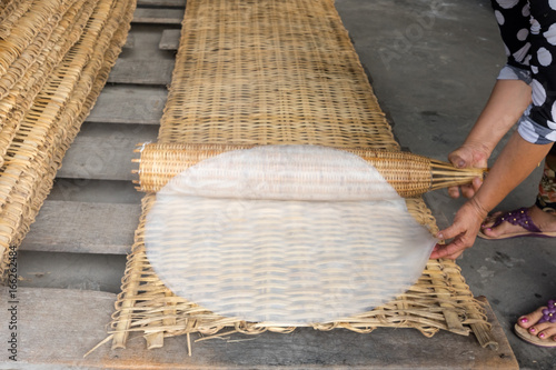 Cooking rice noodles from a flat cake on a wicker bedding. Vietnam, Mekong Delta photo