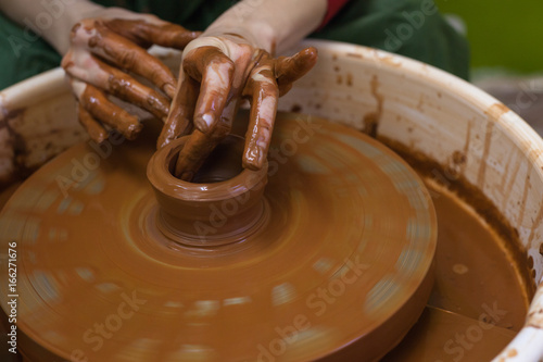 Female hands work with clay. Work in the pottery workshop. The Potter's wheel in operation. Process in the pottery workshop.