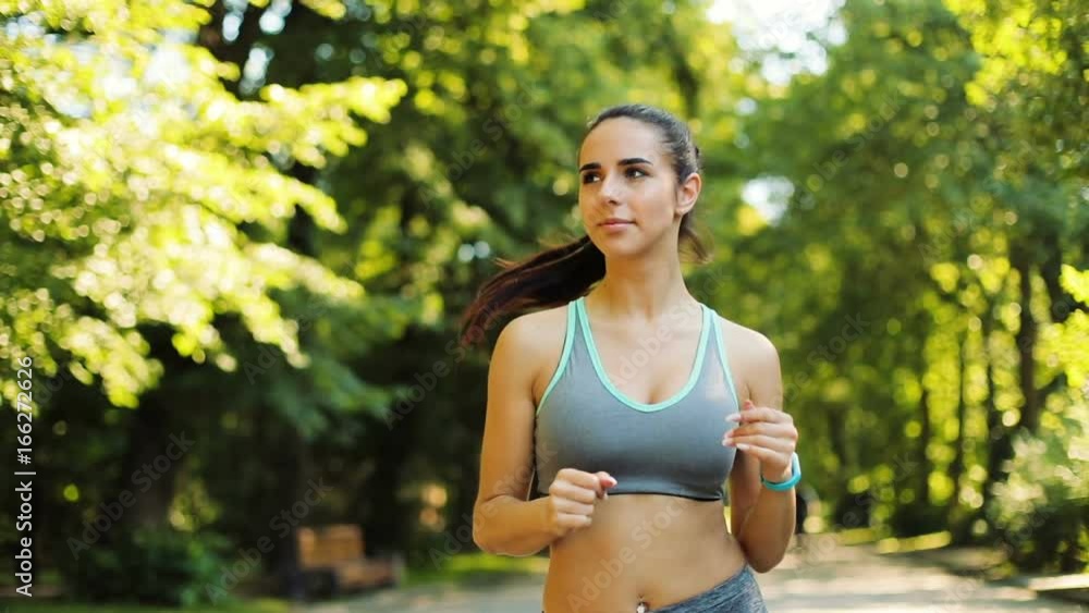 Portrait of young athletic woman running in the green city park on the sunrise background in the morning. Portrait of young athletic woman running in the green city park on the sunrise background in the morning.