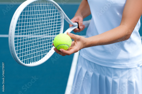 Tennis player holding tennis racket and ball in hand  on the tennis court. © Dmytro Flisak