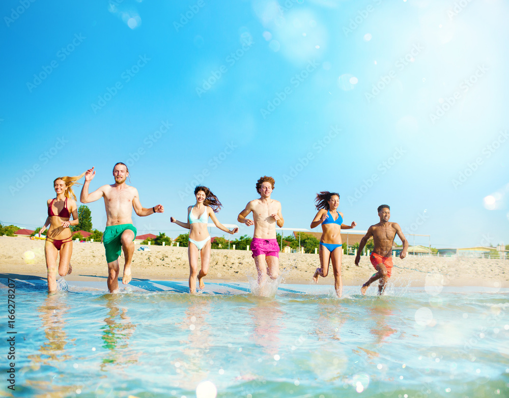 Group of friends run in the sea. Concept of summertime Group of friends run in the sea. Concept of summertime