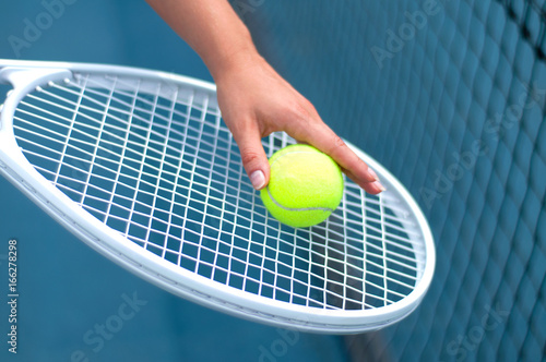 Tennis racket. Player holding tennis ball in hand  on the tennis court © Dmytro Flisak