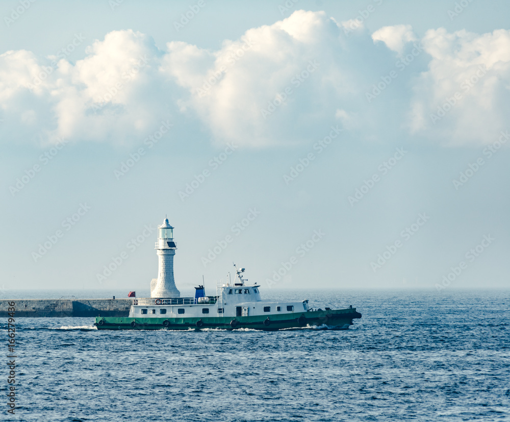 lighthouse with a maritime police boat against cloudy sky,dalian city,china.