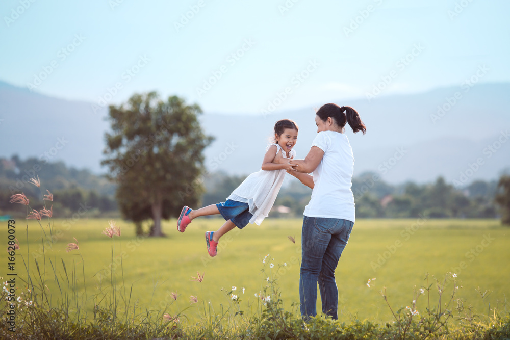 Happy mother holding her kid and spinning around with fun in the field in vintage color tone Happy mother holding her kid and spinning around with fun in the field in vintage color tone