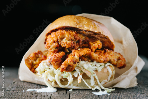 Fried crispy chicken sandwich with coleslaw on dark background
