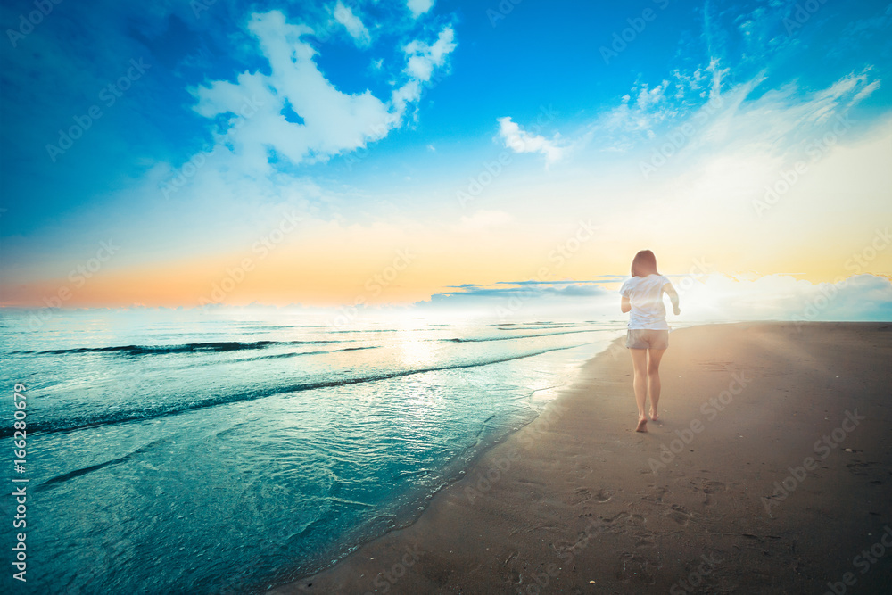 Obraz premium Beautiful young girl running and playing side sea on sand.