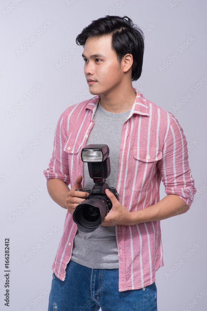 Fototapeta premium Young asian photographer holding digital camera, while working in studio