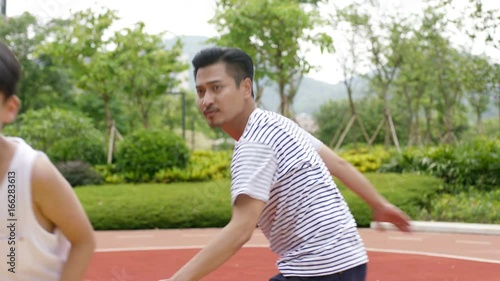 Asian son doing pump fake when playing basketball with father in garden in slow motion