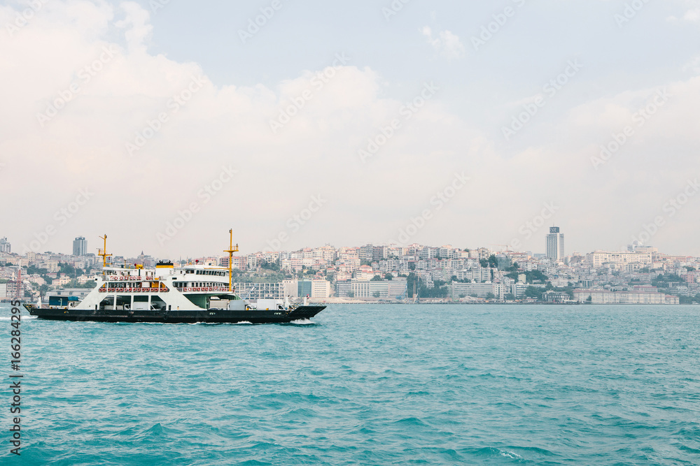 The ship sails along the blue water of the Bosphorus against the backdrop of a beautiful view of the European part of Istanbul. Scenic panoramic view. Travel, rest, vacation.